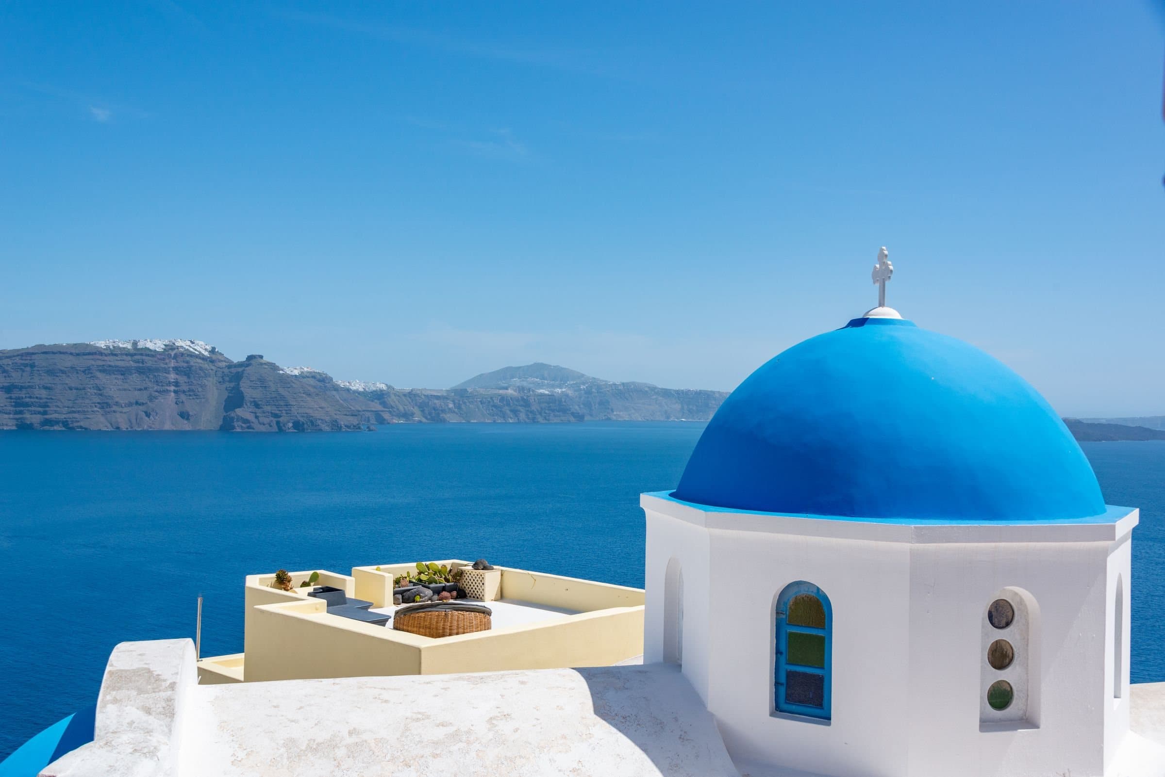 Λευκά σπίτια και γαλάζιος τρούλος πάνω από τη θάλασσα της Σαντορίνης